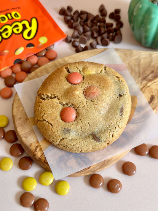 A Reese's Stuffed Cookie on display surrounded by Reese's pieces and chocolate chips