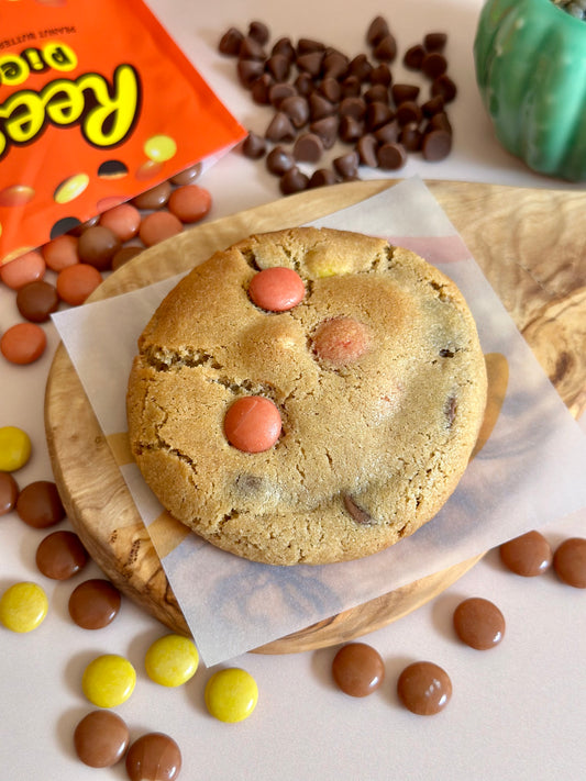 A Reese's Stuffed Cookie on display surrounded by Reese's pieces and chocolate chips